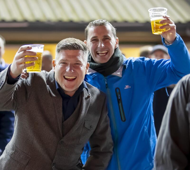 Two gents wrapped up from the cold enjoy a beer at Wolves Races