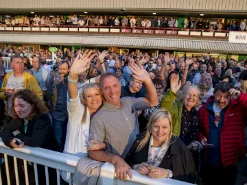 The crowd at Wolverhampton Racecourse wave to the camera