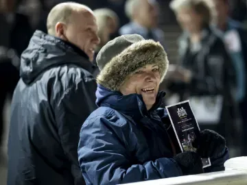 A race goer in a fluffy hat smiling at the trackside at Wolverhampton